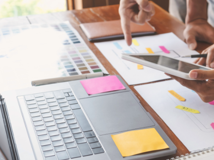 Photo of hands pointing toward a laptop.