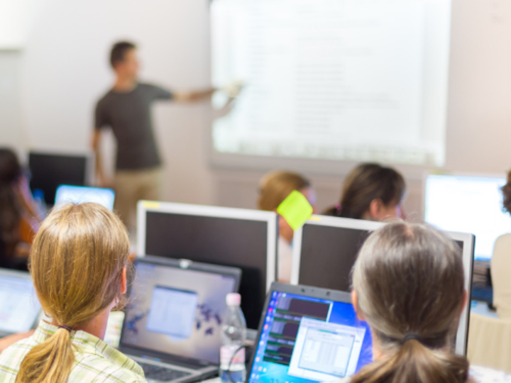 Photo of people in a workshop focusing on a person presenting.